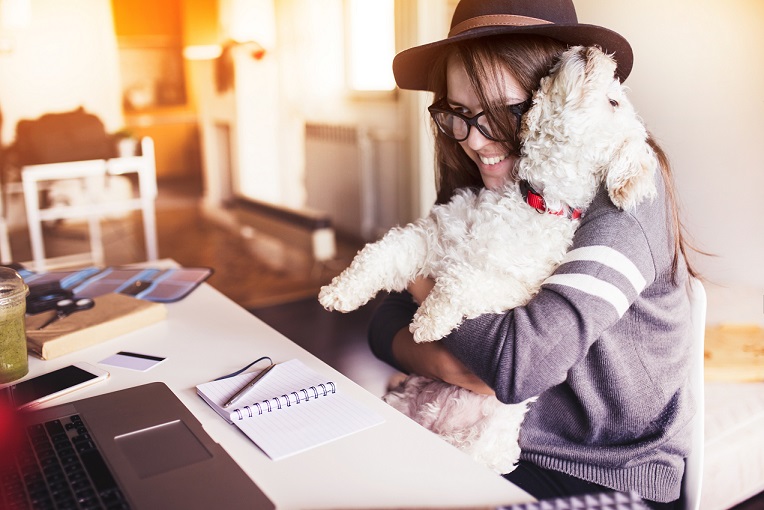 Woman working in her office and hugging her puppy